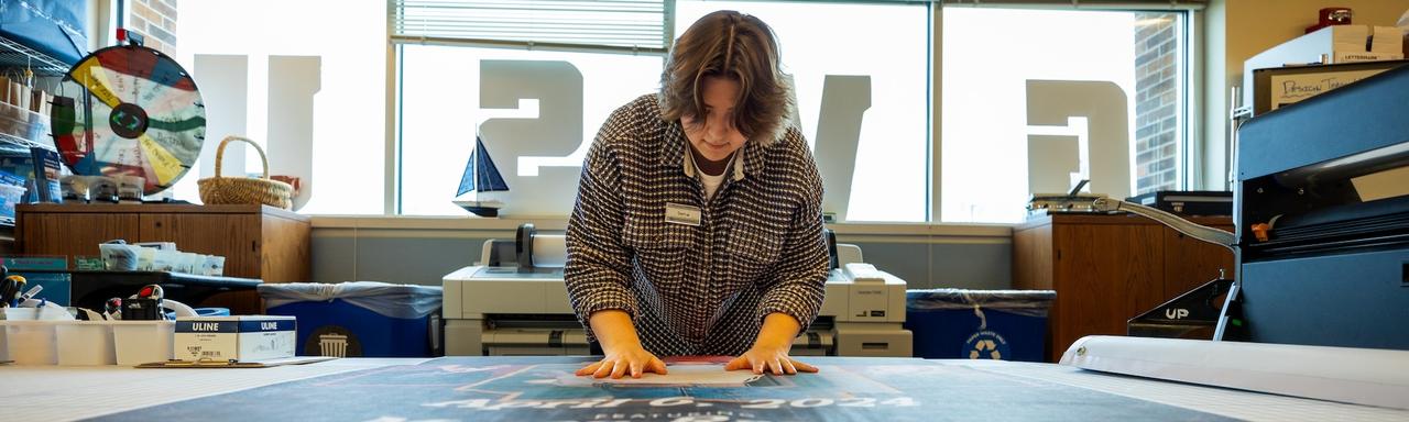 A student laying a large paper banner out on a table